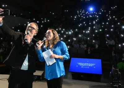 Celebrando auditorio lleno de CIMEDU con luces de teléfonos encendidas.